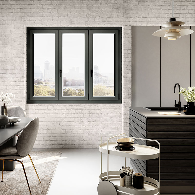 Finestra in PVC color antracite a tre ante del sistema P80 Tecnoplast in una cucina di design con muro in mattoni